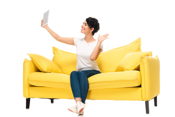 cheerful latin woman holding digital tablet and waving hand while having video call isolated on white  - Photo, Image