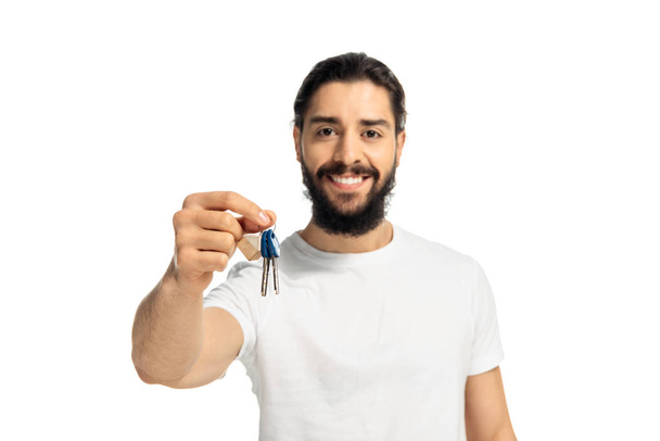 μουσάτος Λάτιν άνθρωπος κρατώντας το κλειδί και χαμογελαστά απομονώνονται σε λευκό  - Φωτογραφία, εικόνα