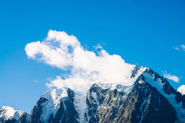Geweldige gletsjer onder de blauwe hemel. Enorme wolk op gigantische prachtige besneeuwde bergen in zonlicht. Sfeervolle minimalistische berglandschap van majestueuze natuur in zonnige dag. - Foto, afbeelding