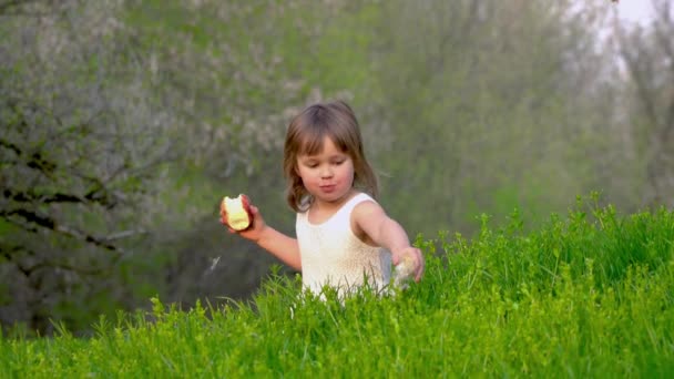 Menina sentada na grama e comer uma maçã
 - Filmagem, Vídeo