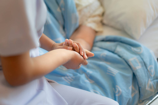 看護師の h を支援する年上の女性の横に病院のベッドの上に座って - 写真・画像