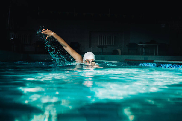 Женщина плавает вольным стилем в бассейне
 - Фото, изображение