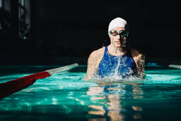 nadador profesional, salpicaduras de agua, gafas y gorra de natación
 - Foto, Imagen