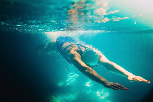 Female swimmer at the swimming pool.Underwater photo. - Фото, изображение