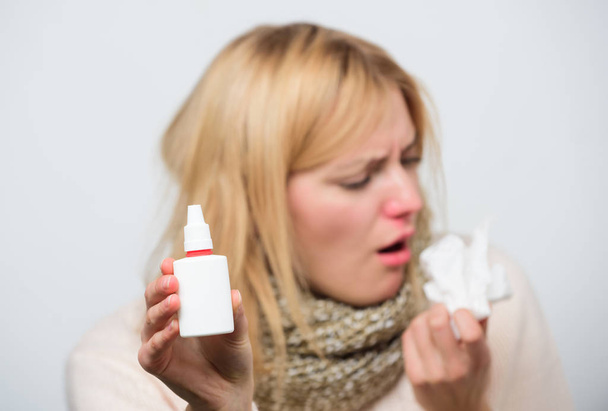 Dispenser bottle. Sick woman spraying medication into nose. Treating common cold or allergic rhinitis. Cute woman nursing nasal cold or allergy. Unhealthy girl with runny nose using nasal spray - Valokuva, kuva