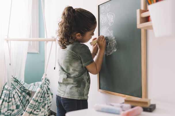 little girl drawing on a blackboard at her room - Photo, Image