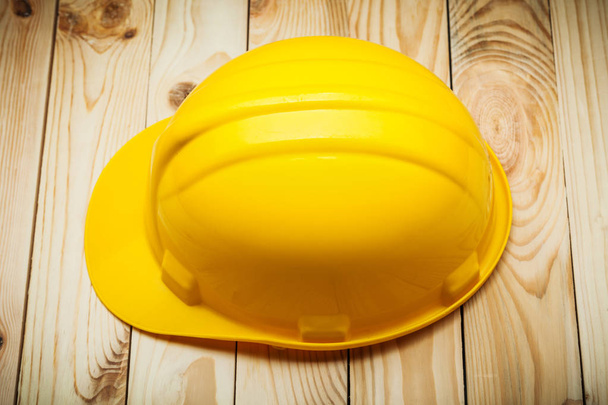 an yellow helmet on wood boards - Φωτογραφία, εικόνα
