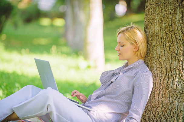 Natural environment office. Work outdoors benefits. Education technology and internet concept. Woman with laptop computer work outdoors lean on tree trunk. Girl work with laptop in park sit on grass - Φωτογραφία, εικόνα