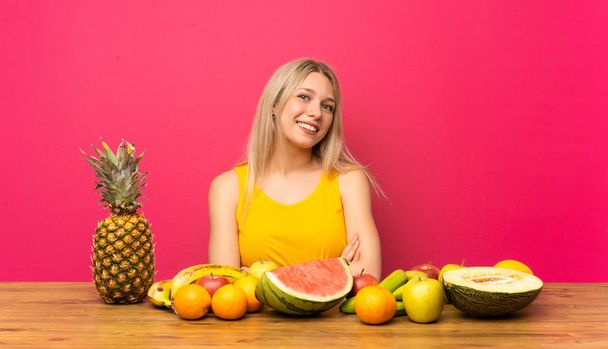 Young blonde woman with lots of fruits laughing - Photo, Image