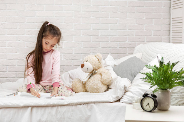 little girl drawing pictures while lying on bed. - Fotoğraf, Görsel