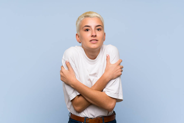 Adolescente menina com cabelos brancos curtos sobre congelamento parede azul
 - Foto, Imagem