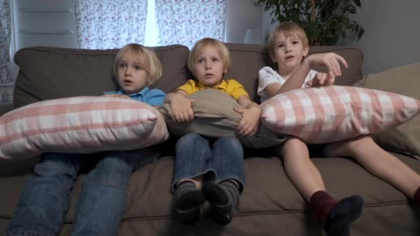 Τα παιδιά αγόρια κάθονται στον καναπέ και βλέπουν τηλεόραση. - Πλάνα, βίντεο