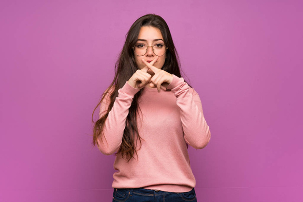 Teenager girl over purple wall showing a sign of silence gesture - Fotó, kép