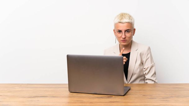 Teenager girl with short hair with a laptop frustrated and pointing to the front - Photo, image