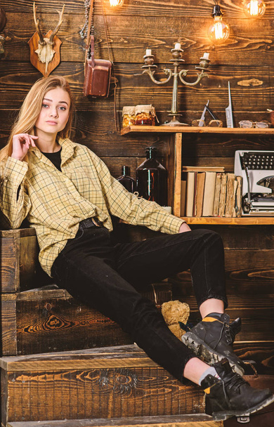 Lady on dreamy face in plaid clothes looks cute and casual. Girl tomboy spend time in house of gamekeeper. Girl in casual outfit in wooden vintage interior. Tomboy concept - Foto, Imagen