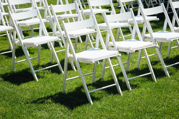 Rows of white folding chairs on lawn before a wedding ceremony in summer - Foto, Imagen