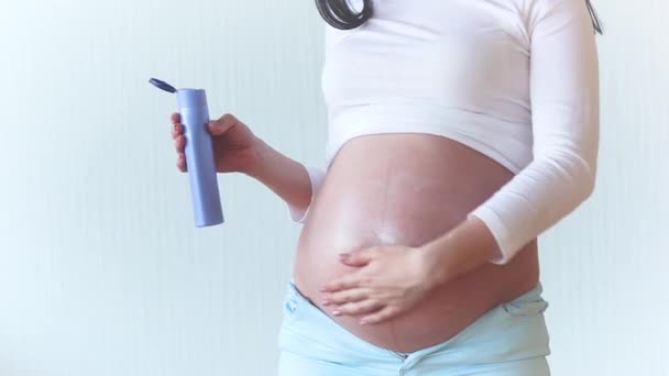 Young pregnant woman indoors. pregnant woman putting on cream  - Felvétel, videó
