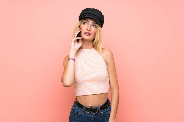 Young blonde woman with hat keeping a conversation with the mobile phone - Fotoğraf, Görsel
