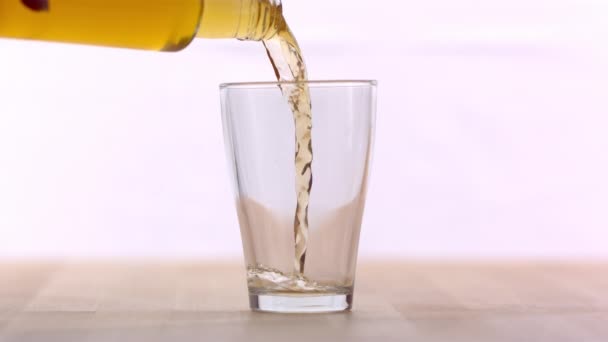 Golden beer pouring in glass on white background, slow motion - Felvétel, videó