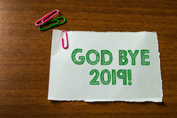 Word writing text God Bye 2019. Business concept for express good wishes when parting or at the end of last year Close up blank stationary paper hold three colored clips lying wooden table. - Photo, Image