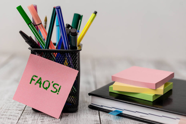 Tekst pisma ręcznego FAQ S. koncepcja oznacza listę pytań i odpowiedzi odnoszących się do konkretnego zagadnienia sprzęt do pisania i arkusze papierowe z książką porządku obrad na drewnianym biurku. - Zdjęcie, obraz