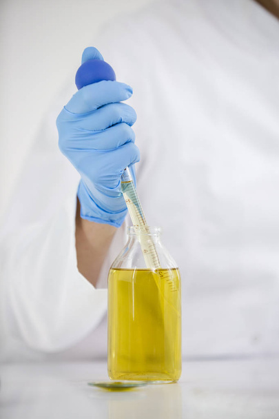 Nahaufnahme eines Wissenschaftlers, der mit pharmazeutischem cbd-Öl in einem Labor mit Glastropfer und einer Schüssel arbeitet - Foto, Bild