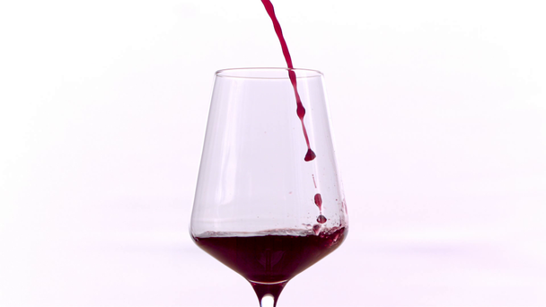 Κόκκινο κρασί που χύνεται σε γυαλί σε λευκό φόντο, αργή κίνηση - Πλάνα, βίντεο