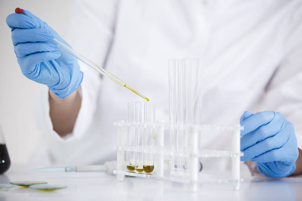 Tudós dolgozik gyógyszerészeti CBD olajat egy laboratóriumban üveg Cseppszámláló és egy tálba - Fotó, kép
