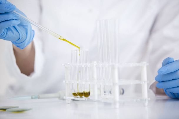 Científico trabajando con aceite de cbd farmacéutico en un laboratorio con cuentagotas de vidrio y un recipiente
 - Foto, imagen