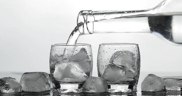 Ömlött fel lövés a vodka üvegből jéggel. Fekete háttér - Fotó, kép