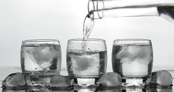 Echando un trago de vodka en un vaso con hielo. Fondo negro
 - Foto, imagen