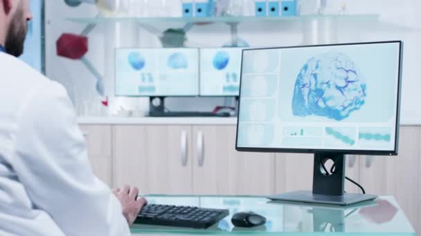 Doktor w swoim biurze wpisując na komputerze w nowoczesnym szklanym biurku - Materiał filmowy, wideo