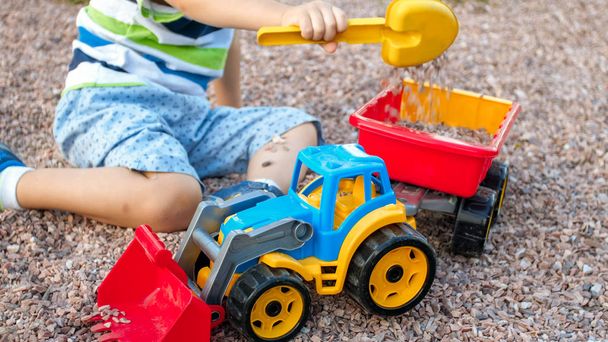 砂と遊んで愛らしい3歳の幼児の男の子の写真と公園でトラックやトレーラー。砂場での子供の掘削と建物 - 写真・画像