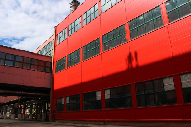 Un grand entrepôt rouge avec de grandes fenêtres pour stocker l'équipement, un centre logistique pour les conditions de livraison d'Incoterms dans une usine industrielle
 - Photo, image