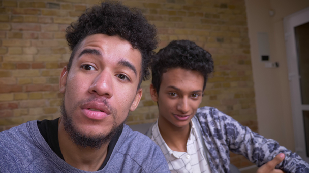 İki genç Afrikalı-Amerikalı ve Hintli erkek blogcular kapalı neşeyle kamera konuşurken canlı akışı Closeup ateş - Video, Çekim