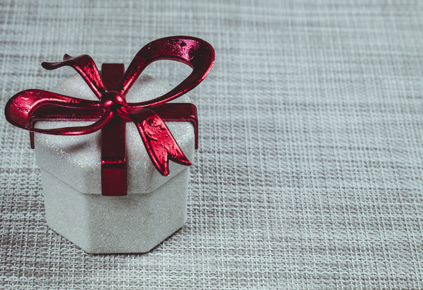 Gift box with a red ribbon on a grey  background - Foto, imagen