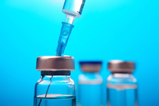 Vaccines and flu shot drug needle syringe on blue background - Foto, Bild