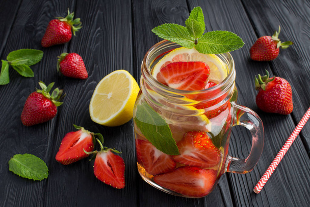 Detox or infused water with strawberry and lemon  in the glass on the black wooden background.Closeup. - Fotoğraf, Görsel