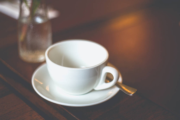 Uzavřete prázdný bílý šálek s talířem a lžičkou na stole - Fotografie, Obrázek
