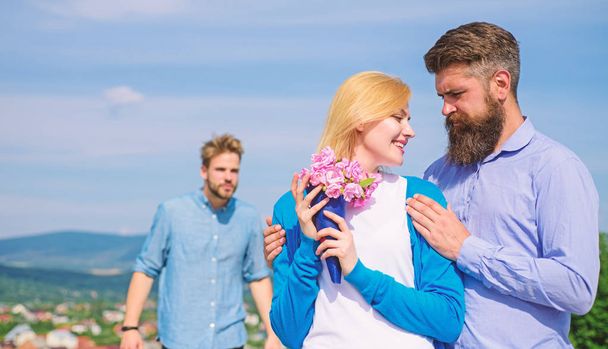 Ex partner watching girl starts happy love relations. Couple in love dating outdoor sunny day, sky background. Leave past behind. Couple with bouquet romantic date. Ex husband jealous on background - Photo, Image
