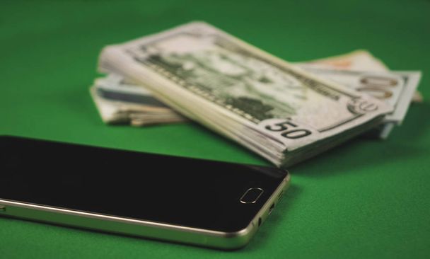 many packs of cash and phone lying on a green background - Photo, Image