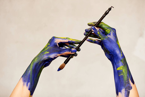 Graceful hands of the artist with a brush. Hands in blue and yellow paint.Creator, creativity. - Foto, Bild