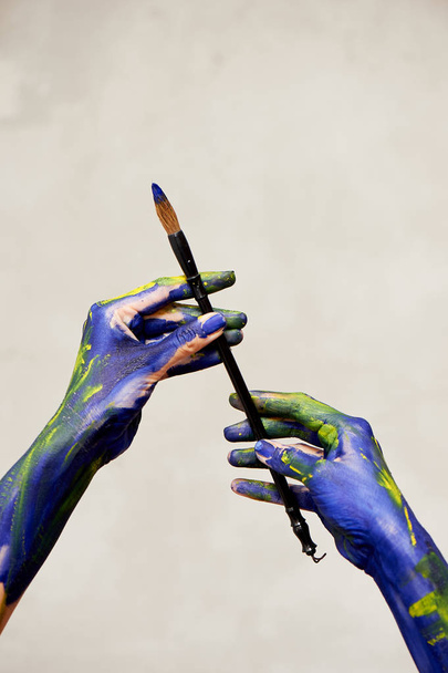 Graceful hands of the artist with a brush. Hands in blue and yellow paint.Creator, creativity. - Foto, Imagen