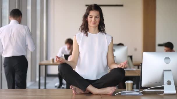 Young calm mindful business woman worker meditate sit on desk - Filmati, video