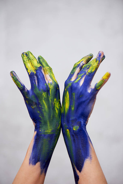 Hands in blue paint with yellow accents, hands of the artist and creative person.Yoga for hands - Foto, Imagen