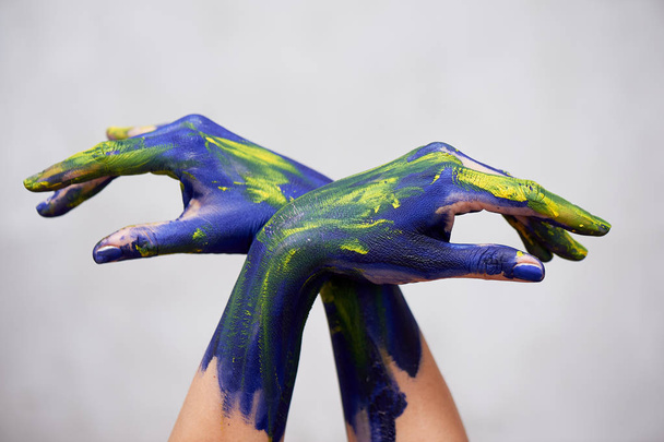 Hands in blue paint with yellow accents, hands of the artist and creative person.Yoga for hands - Photo, image