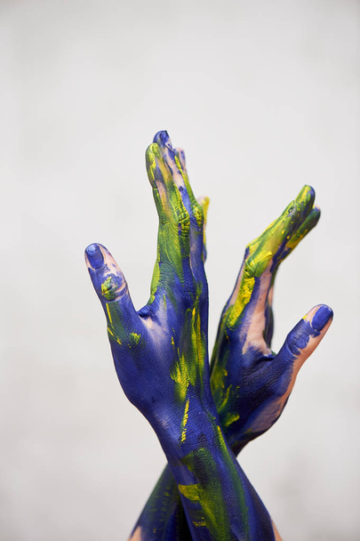 Ręce w niebieskiej farby z żółtymi akcentami, rąk artysty i twórczej osoby. Joga dla rąk - Zdjęcie, obraz