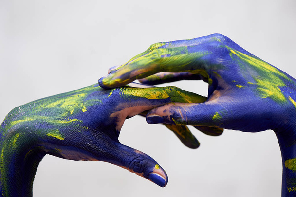 Hands in blue paint with yellow accents, hands of the artist and creative person.Yoga for hands - Photo, image