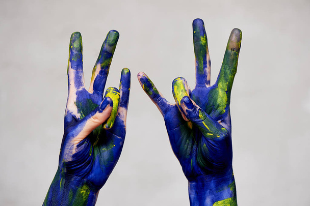 Hands in blue paint with yellow accents, hands of the artist and creative person.Yoga for hands - Zdjęcie, obraz