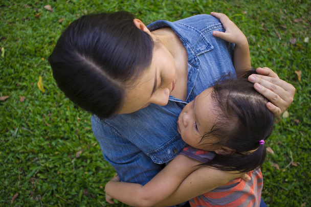 泣いている小さな娘を抱きしめて落ち着く若い母親、アジア - 写真・画像